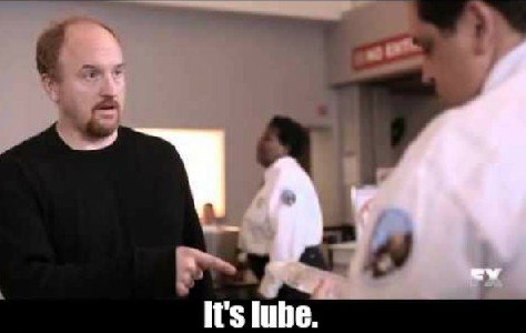 Screen shot from TV show "Louie". Louis C.K. at airport security, pointing to his stuff and speaking to a T.S.A. agent. Caption reads, "It's lube."