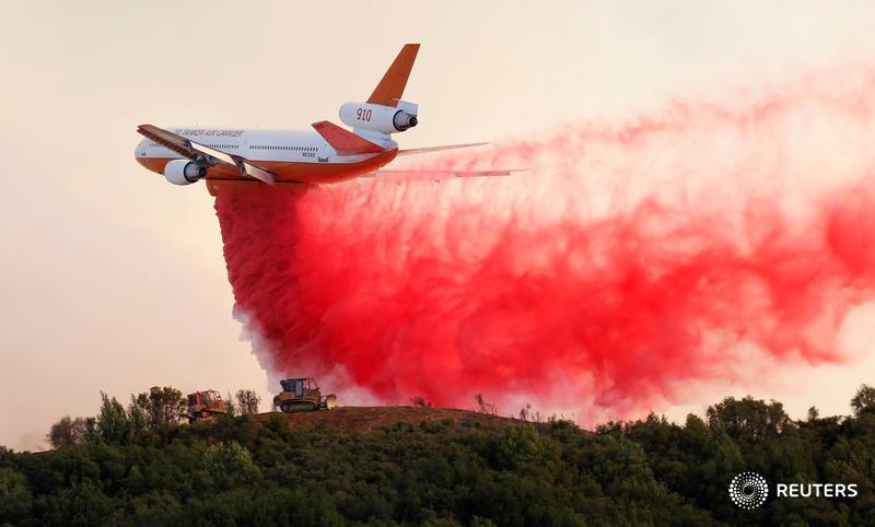 A DC-10 air tanker drops fire retardant along the crest of a hill, as firefighters battle the Mendocino Complex fires in California