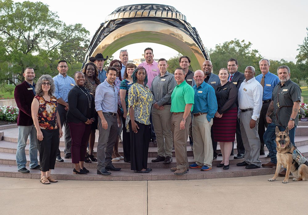 21 veterans standing in front of the Aggie Ring statue