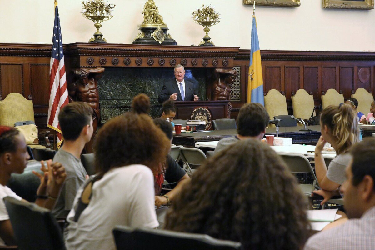 The Mayor speaking to students seated at a table.