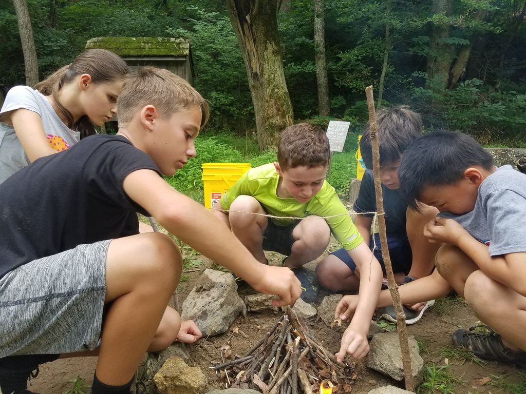 DENatureSociety's tweet photo. Child vs. Wild campers (ages 9-12) working together in a campfire building task. They had 4 minutes to get the fire high enough to burn through the twine! #CampPicOfTheDay #DelNatureSummer #DelNatureSociety #DelNatureSummerCamp #Take5Outside https://t.co/VNYDlds6Gf