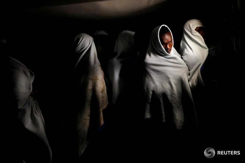 Migrants rescued on the Mediterranean stand on board before arriving at port in Spain