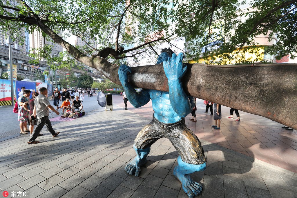 ChinaDaily's tweet photo. Citizens and tourists marvel at the mighty giant "hulk" sculpture in Chongqing lifting a tree trunk. (Photo: IC) https://t.co/CWg8kQQaV8