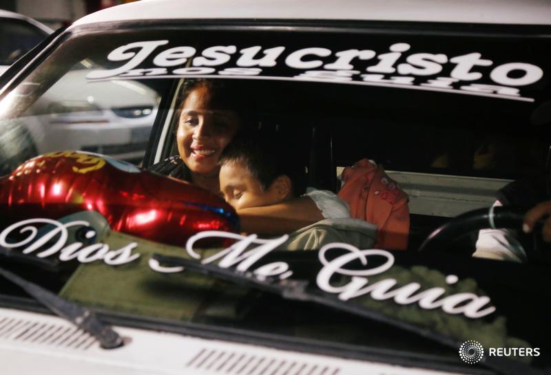 Elsa Ortiz, who had been separated from her son Anthony David Tobar at the U.S. border, holds him after they were reunited in Guatemala. The writing on the windshield reads 'Jesus Christ, God guide me.'