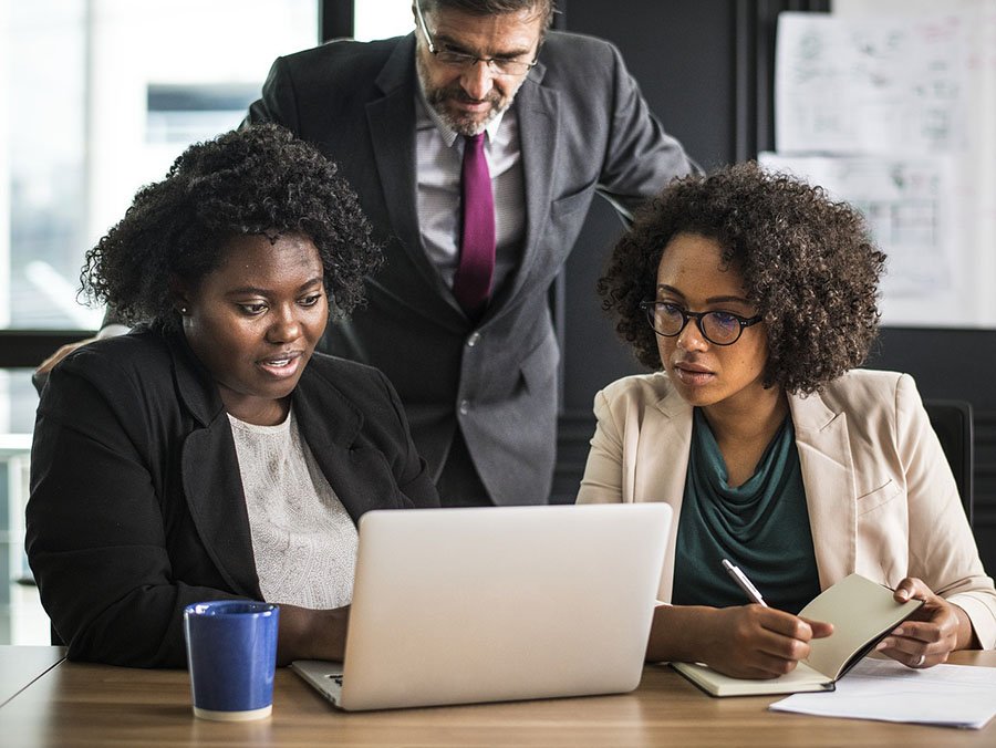 two black women in suits conferring over a laptop