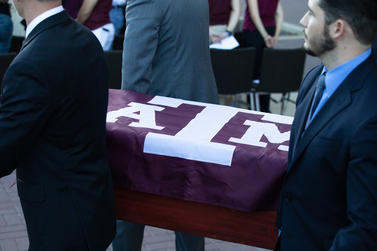 Texas A&M flag draped over a casket being carried by four men