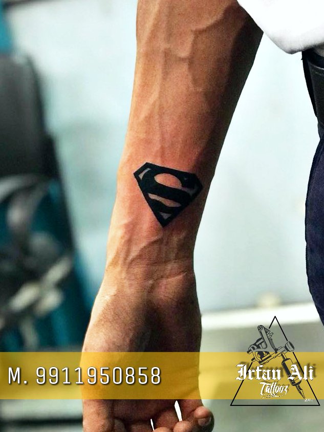 Fine line superman logo tattoo on the inner forearm.