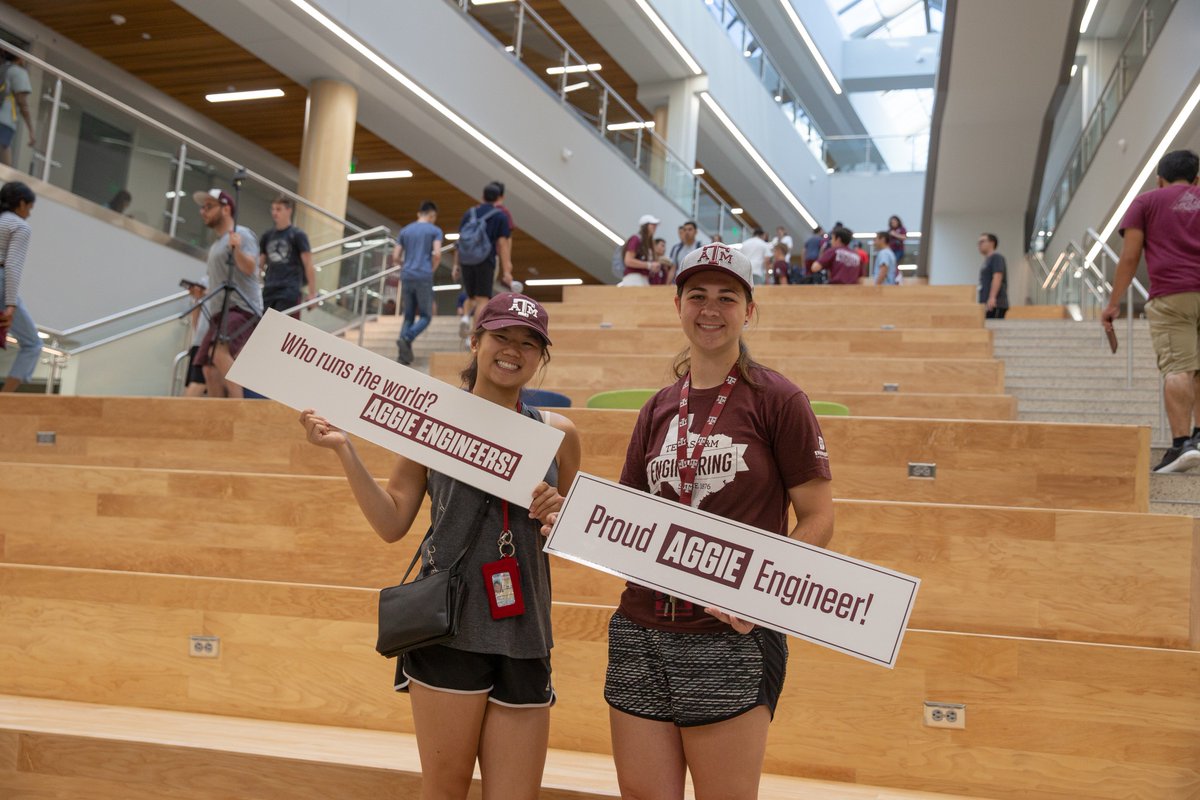 two aggies holding signs that say Proud Aggie Engineer