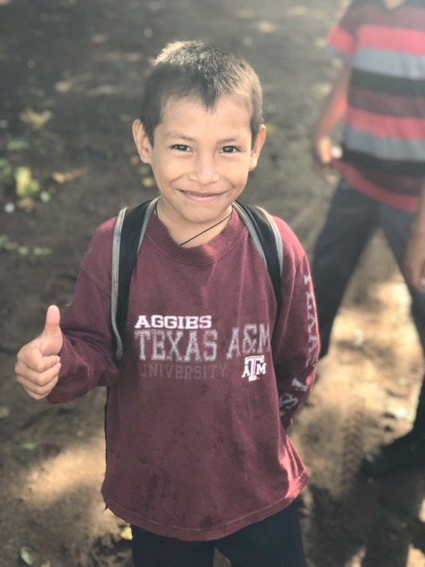 young guatemalan boy wearing a texas A&M shirt and smiling
