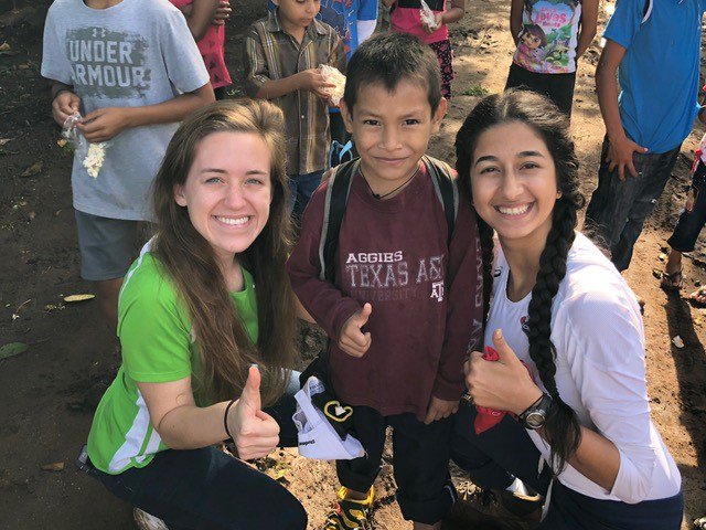 two Aggies taking a photo with a smiling boy wearing a TExas A&M shirt