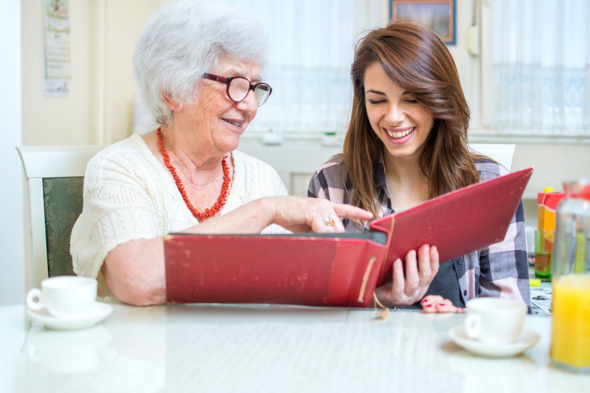 older woman looking at photo book with younger woman