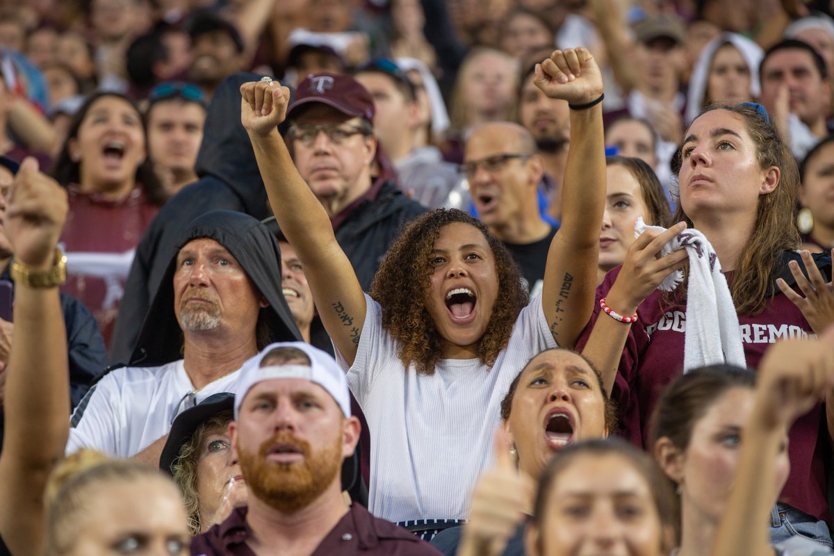Excited Aggies with a woman in the middle of the photo with her arms in the air in celebration
