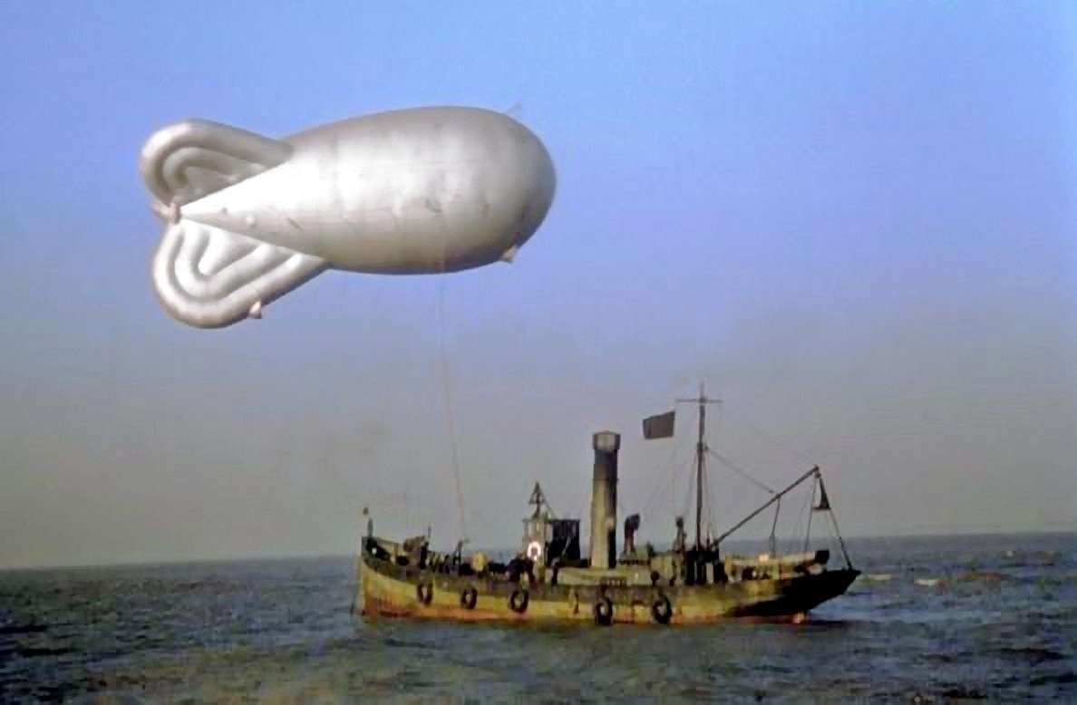 StuartHumphryes's tweet photo. There is something quite extraordinary about this little rusty tugboat with its enormous barrage balloon that makes it look like a scene from a Terry Gilliam movie! Yet it actually harks from the 1940s. What a brilliant image! https://t.co/bj0FbGSVwJ