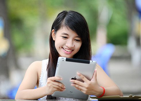 young girl reading on her tablet, smiling