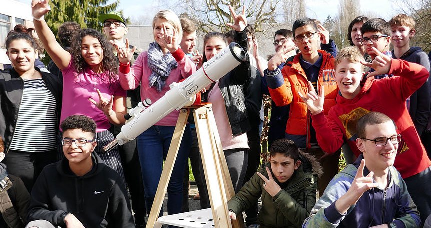 SSVI students gathered around a telescope looking excited.