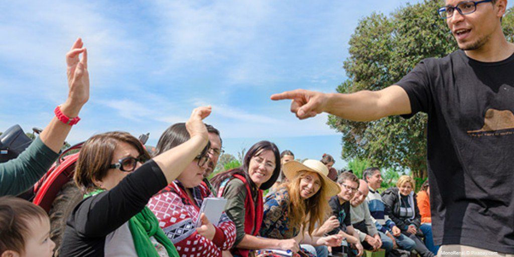 A man pointing to a person with a question at an open forum.