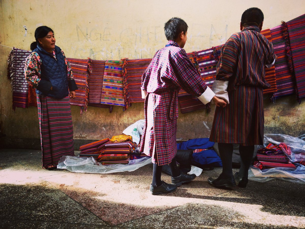 MaidenBhutan's tweet photo. A woman displays her goods of beautifully handwoven textil at the market. Her sister from Pemagatshel, a district in the east, sent it here as these fetch a decent profit in the capital. Within minutes of the display,  people began flocking to admire $ haggle for the best price. https://t.co/Ug8mrjATca