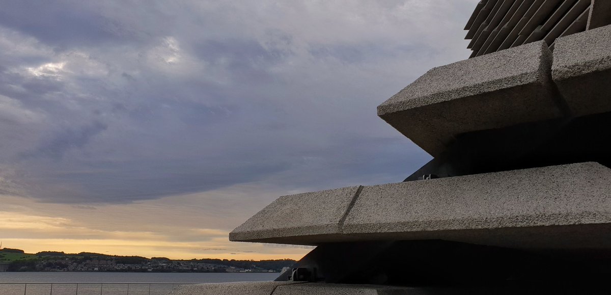 close up of V&A Dundee's concrete panels with eh dusky blue and gold clouds beyond.