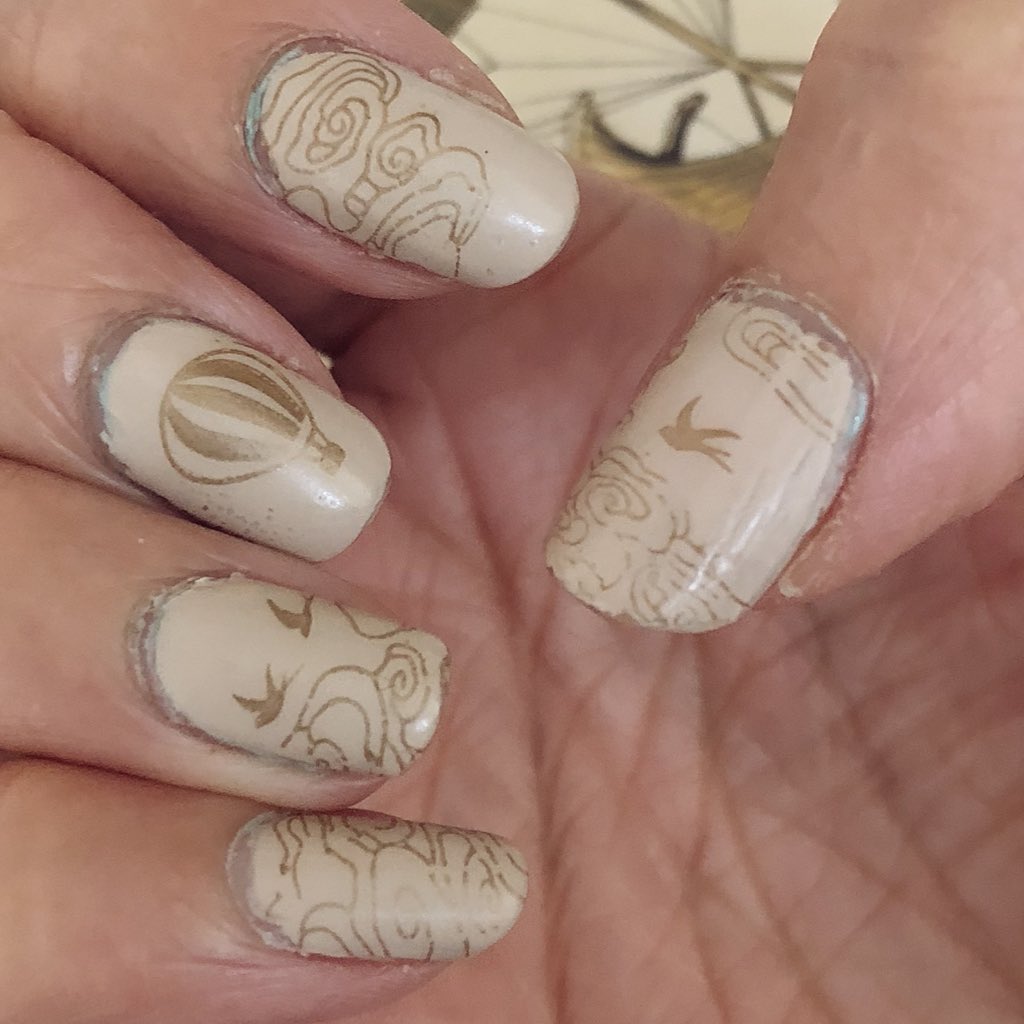 Closeup of cream and gold nail art with hot air balloon, cloud patterns and birds