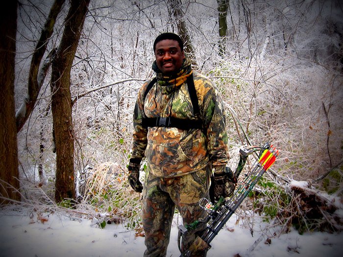 Black male outdoors on hunting clothe holding until tool