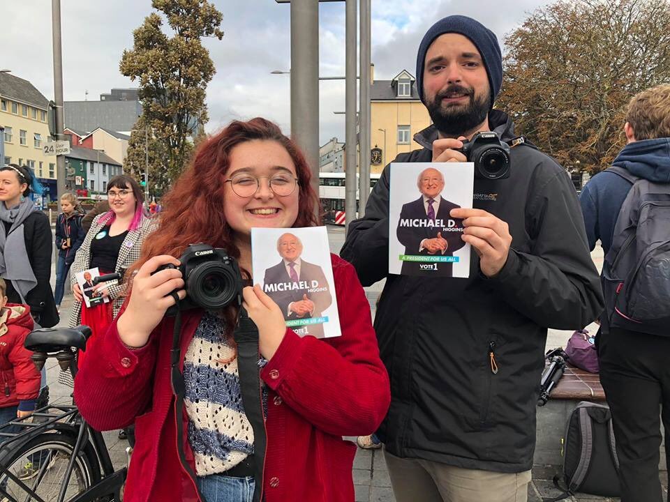 Two people holding campaign literature and cameras in Galway