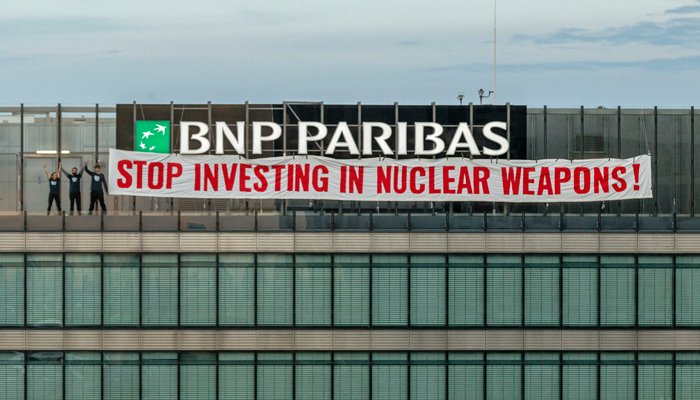 PressenzaIPA's tweet photo. ICAN activists unroll 20 meter long banner on top of BNP Paribas building in Germany @DontBankonBomb @BNPParibas #ChangingWorld #NuclearBan #CapturetheChange https://t.co/17nNSmoz62 https://t.co/VKrAoFacnp