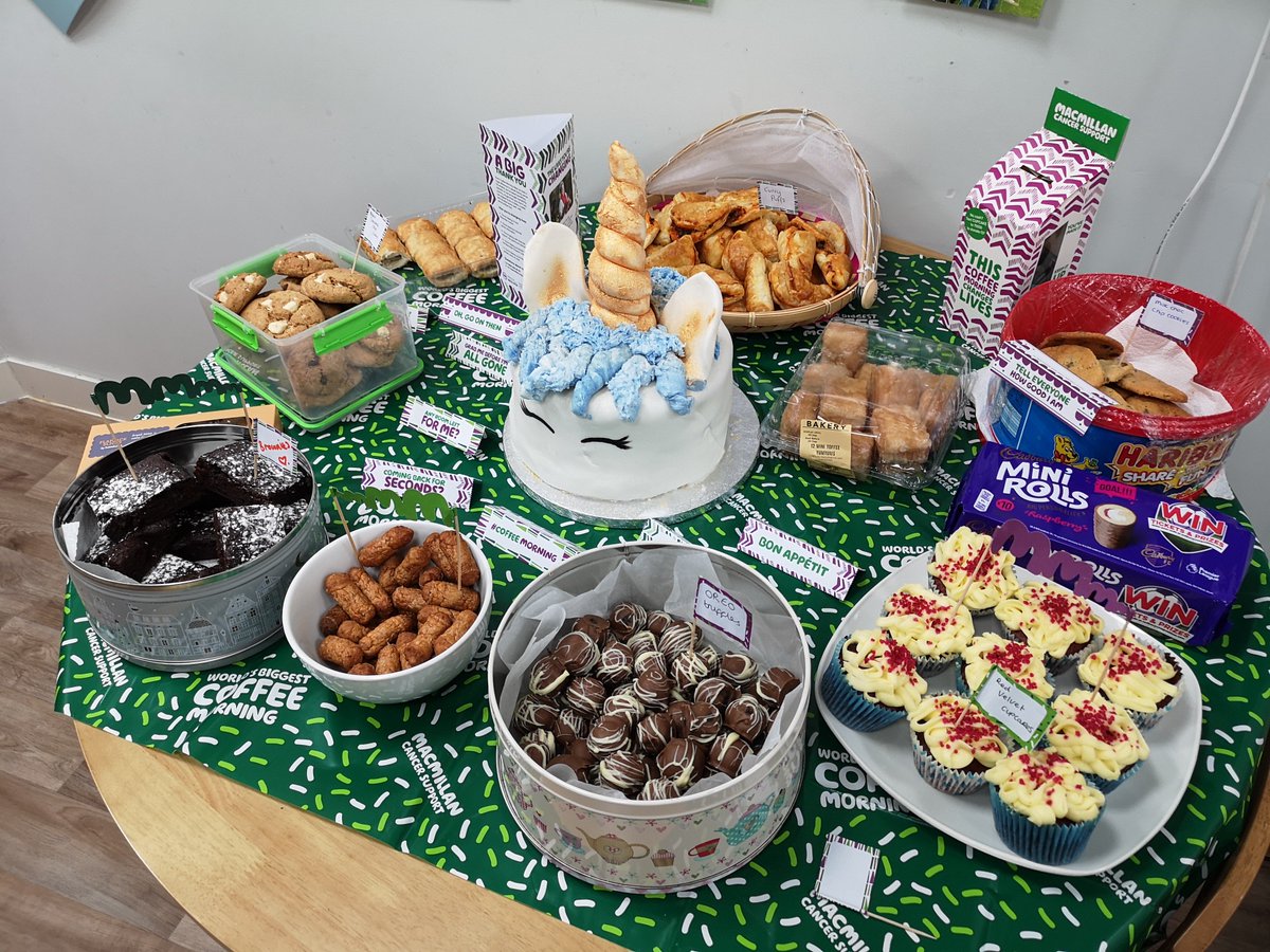 A selection of cakes, brownies and cookies on a table with a large unicorn cake in the middle