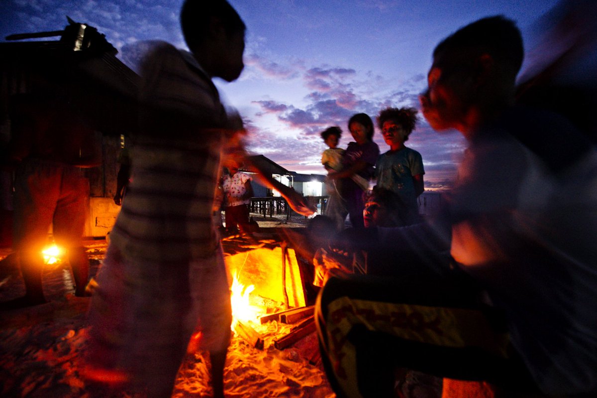 Villagers from Salpele cook fish. There is nickel mine across the water which will destroy their fishing grounds when it opens. Some residents will be employed by the mine and welcome the move. Others are more long term in their thinking and strongly oppose it.