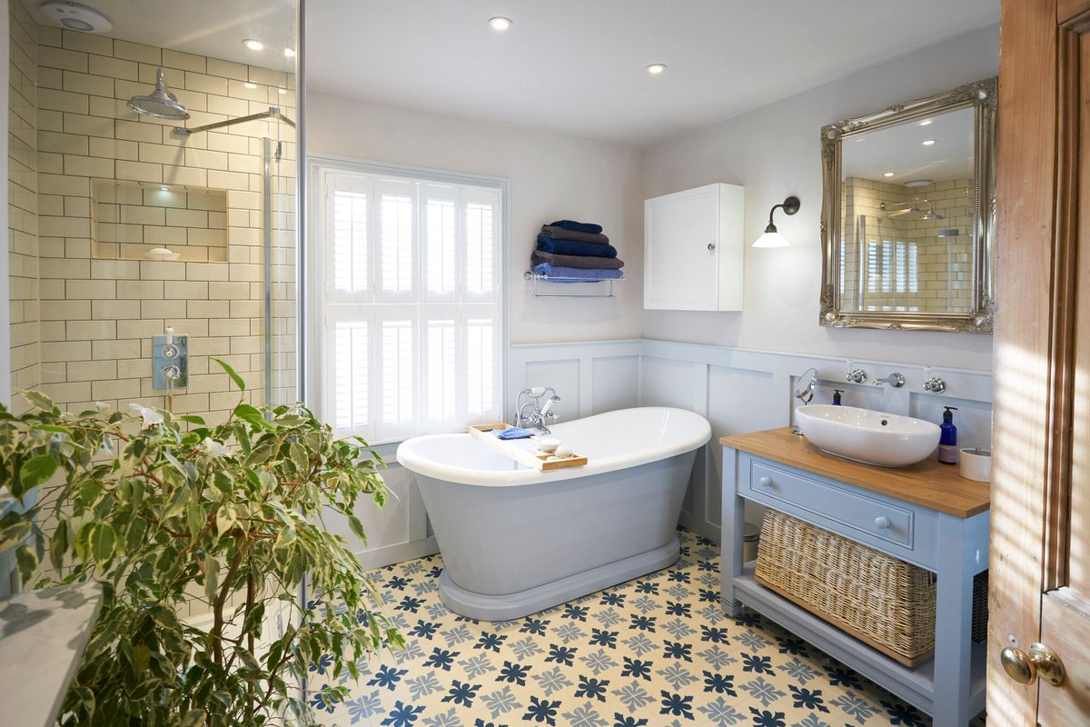 The blue wooden cabinets in this bathroom give it a cosy, country feeling, especially when paired these tiles - we love this design. #bathroominspo