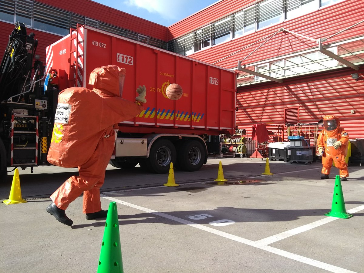 Twee gaspakdragers gooien een balletje in de kazerne… Ze oefenen op wat er gebeurt als ze zich inspannen in zo’n oranje pak. Het gaspakteam wordt ingezet bij een incident met gevaarlijke stoffen, als er dus radiologische, biologische of chemische risico’s zijn.