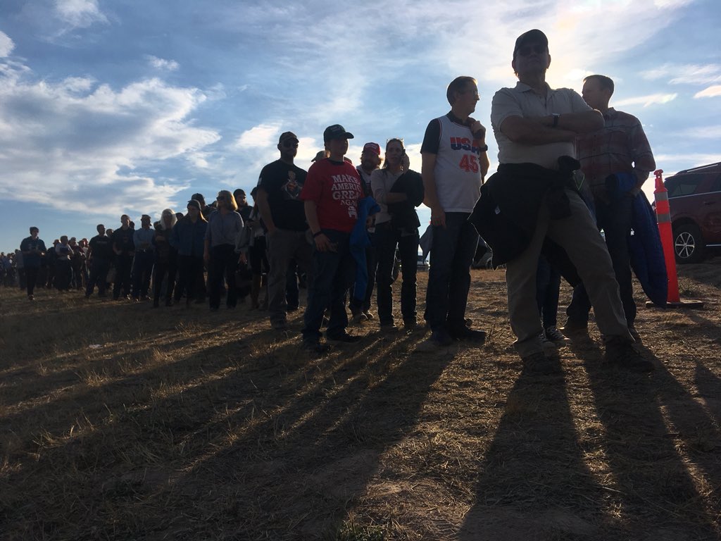 TimGoessman's tweet image. Line is wrapped around event parking area, buses still bringing supporters. 1.5 hours until Trump is scheduled to speak #trumpmt #mtpol