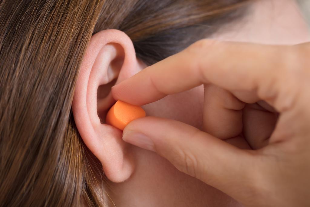 Woman putting an earplug into her ear.
