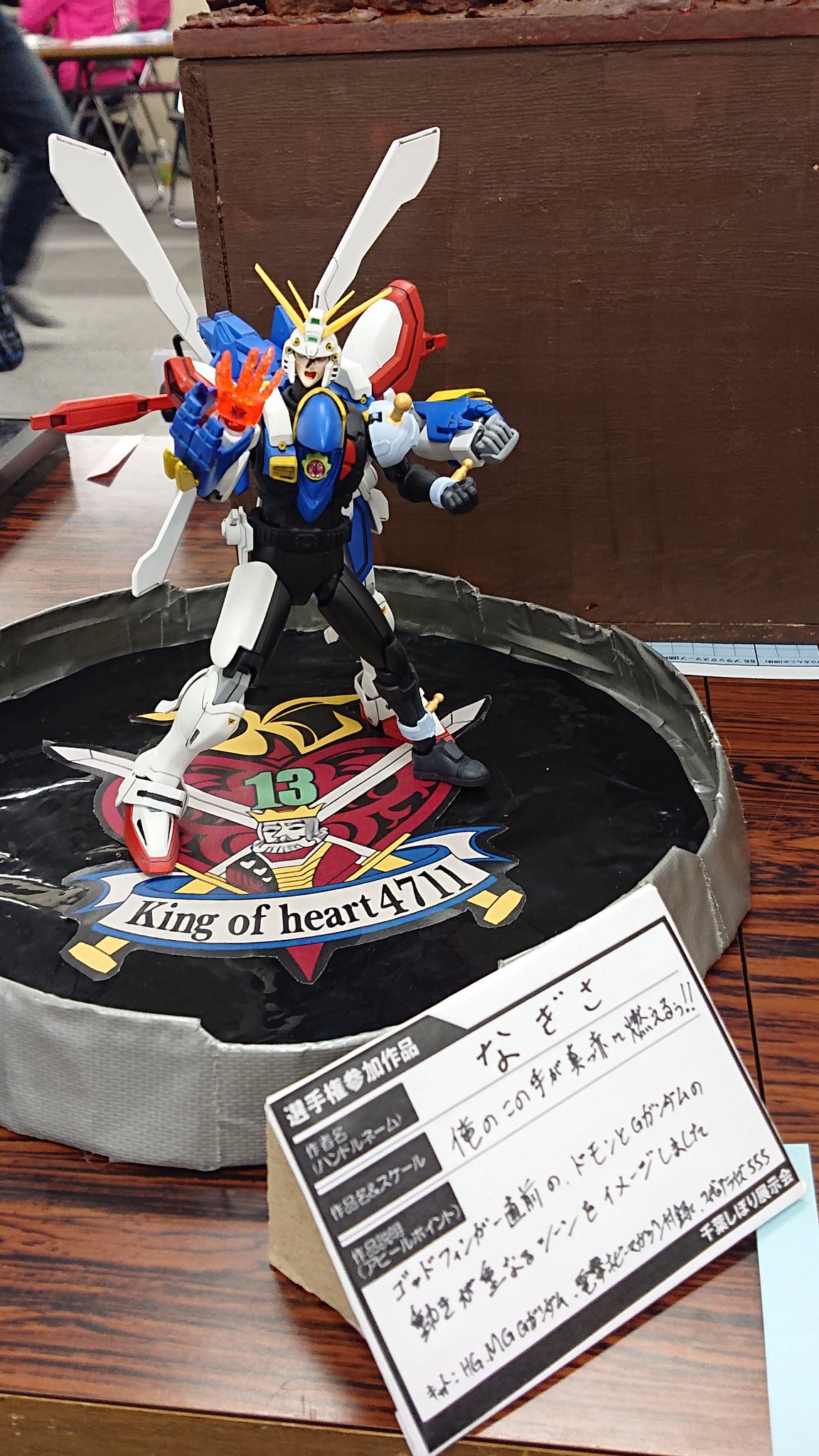 さくしゅん なぎささん作 ゴッドガンダムです 人機一体となったドモンの再現ですね ドモンは仮面ライダー555を改造してできたみたいです 確かに肩見るとわかりますね 台座はモビルトレースシステムを再現しており 中央にキングオブハートの紋章が