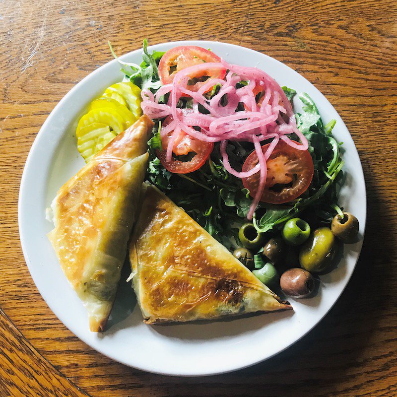 LampPDX's tweet photo. On the specials board this week: $1 off an order of our Spanakopita 12pm - 3pm! Rich flaky filo dough filled with spinach and feta. Includes arugula salad with pickles and olives. 😋 https://t.co/2tT8AYKBvu
