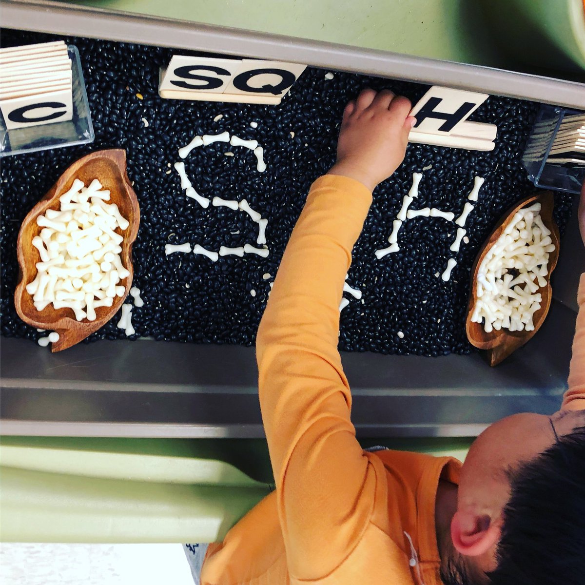FDK_Lightning's tweet photo. Letter building in the sensory bin with black beans and acrylic bones. #dlmb #letterbuilding #sensoryplay #kindergarten https://t.co/PyAKw3y6uw
