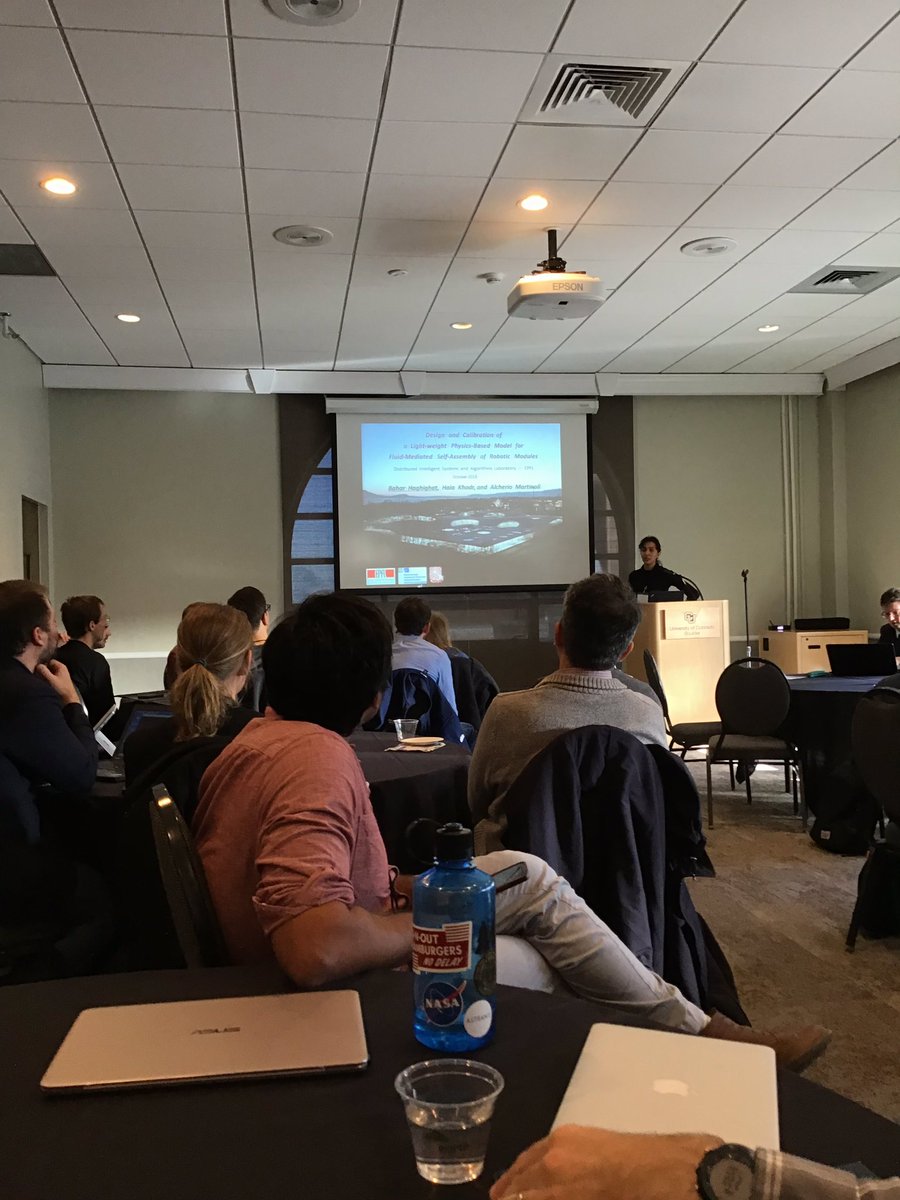 DARS2018Boulder's tweet photo. Bahar Haghighat from @EPFL shows #DARS2018 robotic "lillies" that self assemble in turbulent fluid flows. Don't worry - her talk is much smoother than the water the robots float in, and I'm sure our understanding of the content will be as tight as the structures the robots build. https://t.co/V7zWBTWz8r