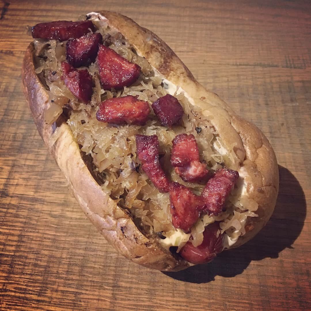 “The Royal” beef and hemp hotdog on a marbled bun. House made Island spread, apple bacon sauerkraut topped with fried capicola ham😍