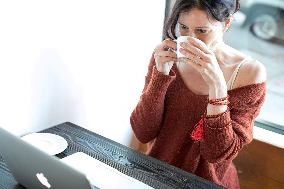 a woman at a laptop drinking coffee