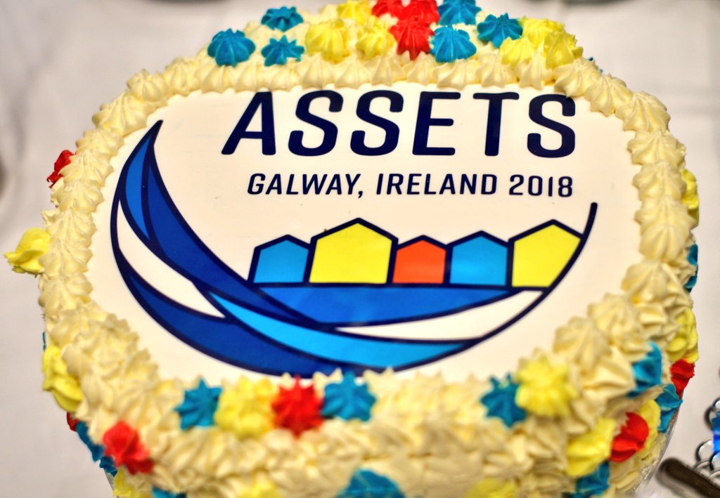 close up photograph of a cake iced with the #ASSETS2018 conference in Galway Ireland.