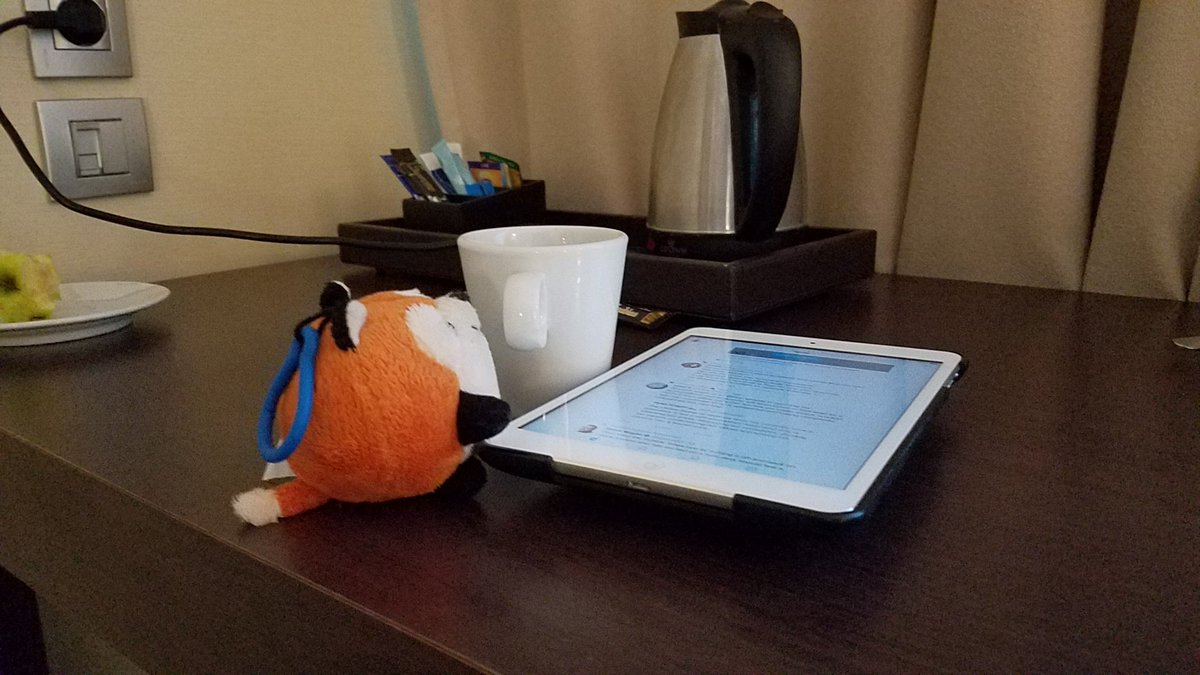 a plush fox with coffee working on a tablet computer