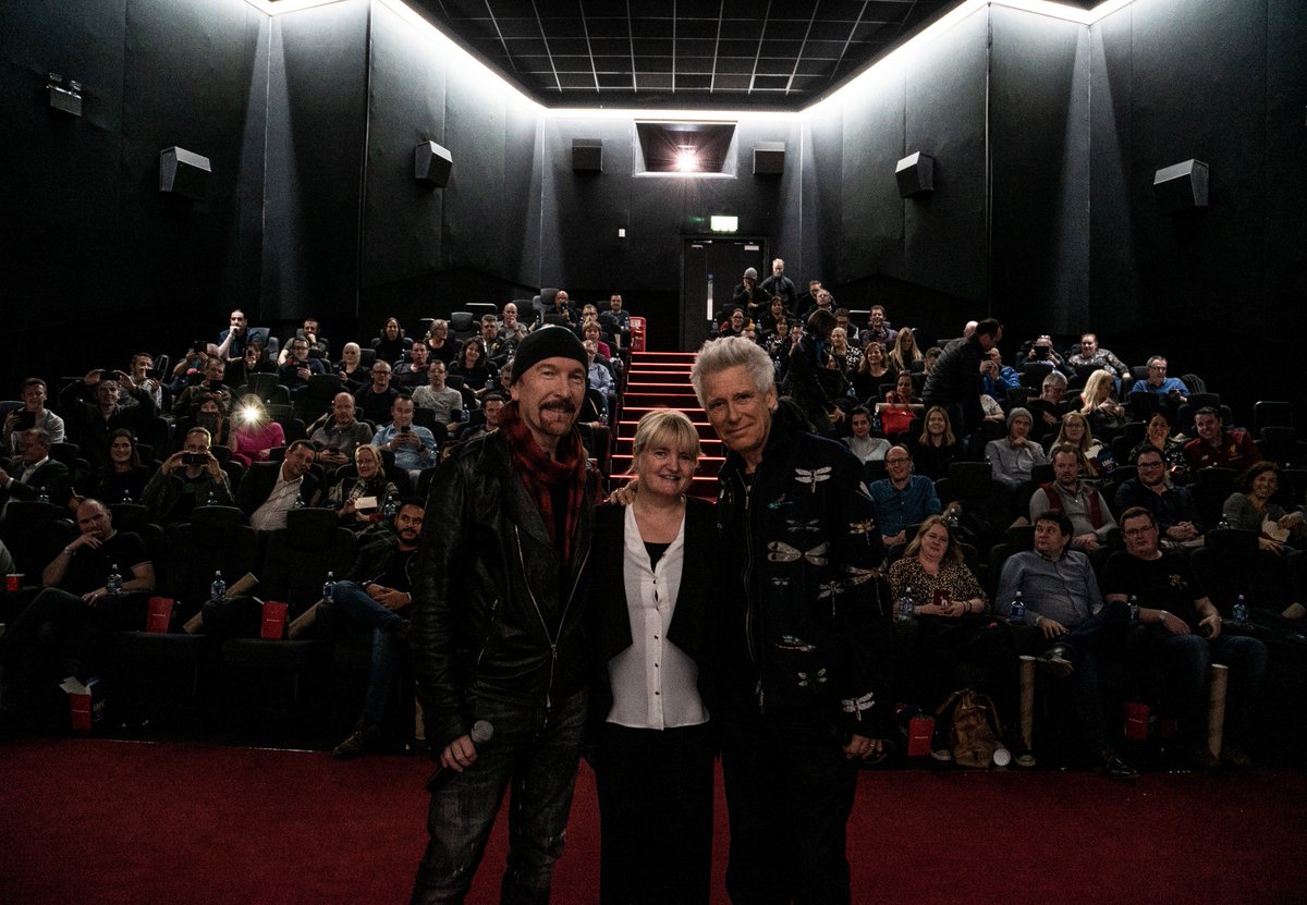 U2's tweet photo. Adam &amp; Edge with Sandra the general manager, and usher at the original premiere, @SavoyDublin tonight for a special screening of Rattle and Hum, on the eve of the 30th anniversary of the world premiere… also at The Savoy in Dublin.  
#U2 #rattleandhum #musicaljourney https://t.co/aWCGR74fg3