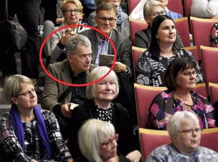 Sajam knjiga u Finskoj.
Predsednik Finske sedi na stepenicama u sali pošto nije bilo dovoljno mesta.
Nekoliko posetilaca se ponudilo da ustupi mesto predsedniku, ali je on učtivo odbio.