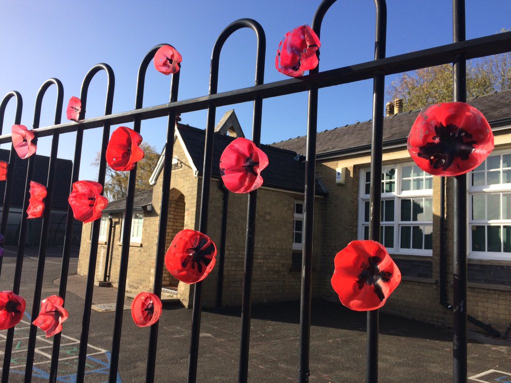 SciHiEd's tweet photo. Beautiful poppies on the fence of @OverPrimary ... made out of old plastic bottles!  So effective on this important day #Armistice #LestWeForget #cambridgeshire https://t.co/gXJGMhCcX9