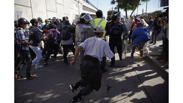 6News's tweet photo. Migrants approaching the U.S. border from Mexico have been enveloped with tear gas after a few tried to breach the fence separating the two countries. https://t.co/DbeNoFD8qS https://t.co/X2hPJu51vZ