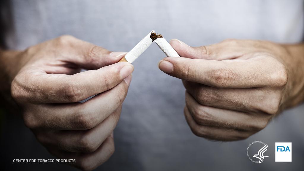 Man breaking cigarette in half.