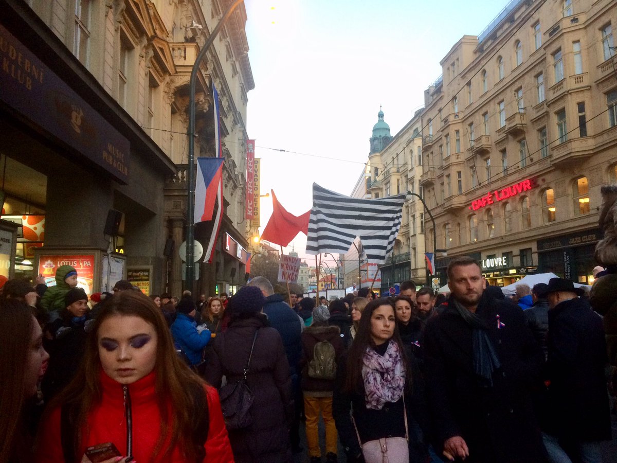 Na Národní třídu právě dorazil průvod demonstrantů. Ulice se plní, projít k podloubí a zapálit svíčku u památníku začíná vyžadovat trpělivost.