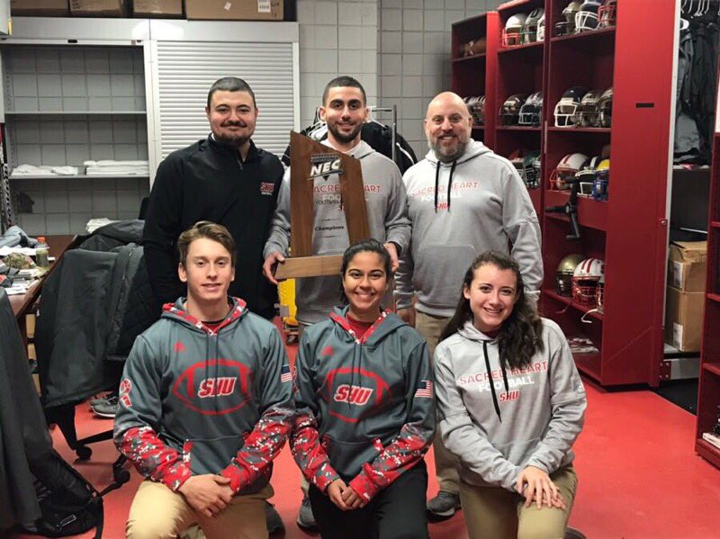 SHU_Equipment's tweet photo. Our staff with the @SHU__Football NEC Champs trophy. Proud of the entire team, especially our student managers who work hard to help this team. #champs https://t.co/lEAyUaEsKo