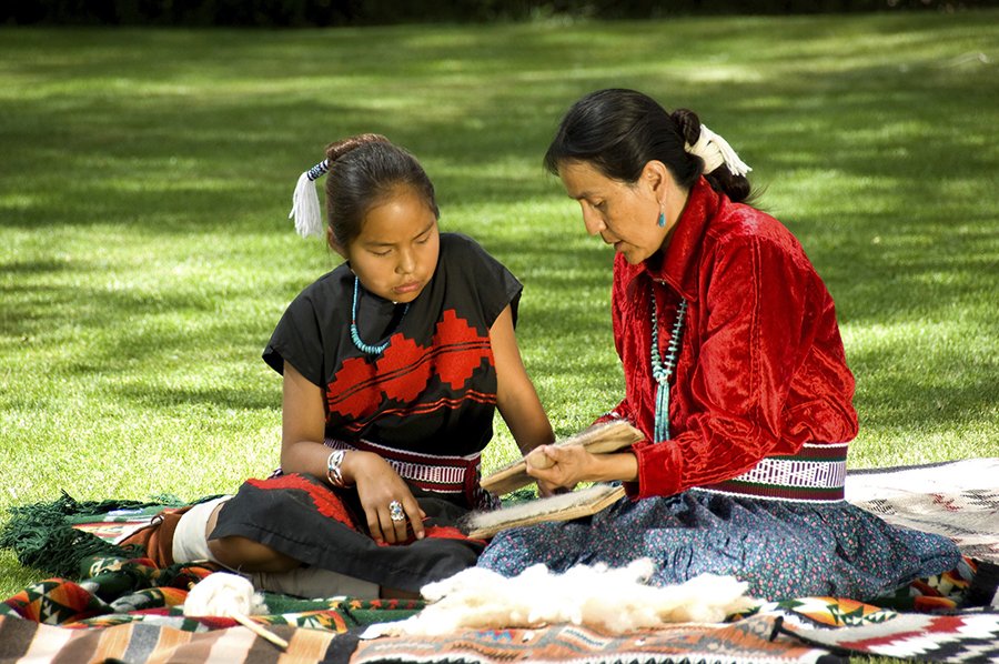 Native American women sitting in a park, crafting together