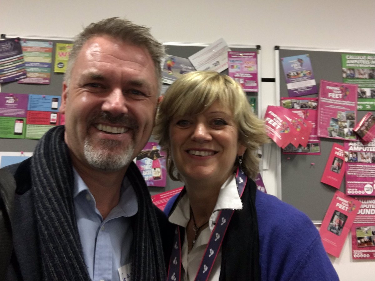 Gavin and Corrine. Standing in front of a notice board covered in flyers and messages of support.  Both are grinning