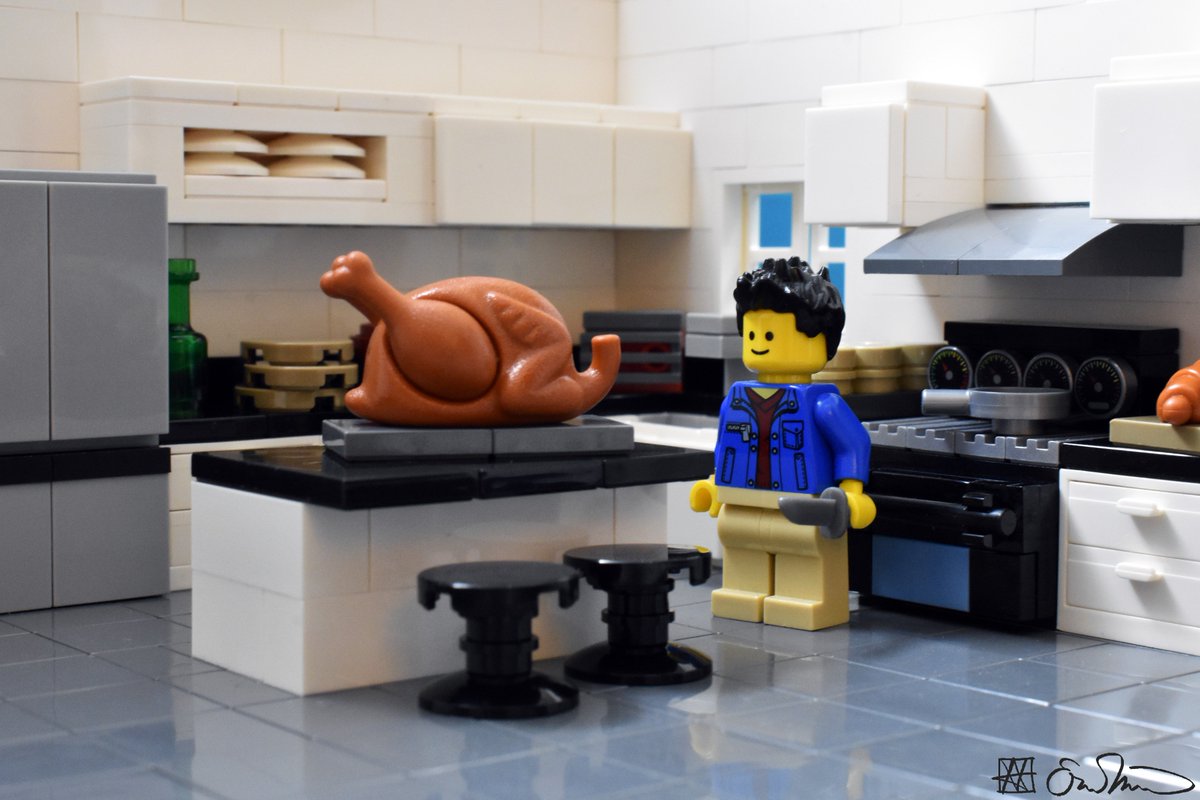 LGS stands beside a large turkey and his holding a knife. He is cooking in a family member's spacious white kitchen.